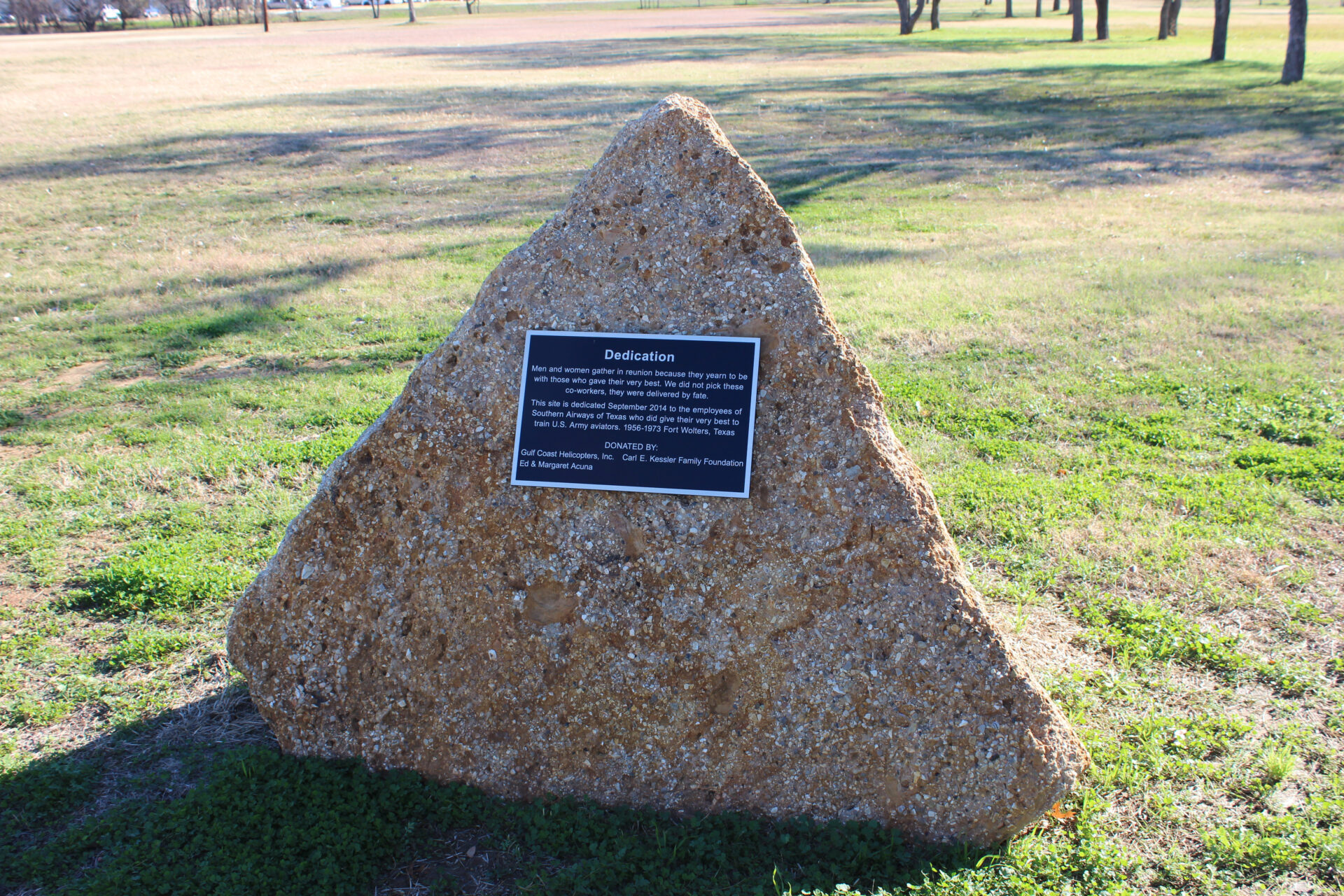 A stone with a plaque on it in the grass.