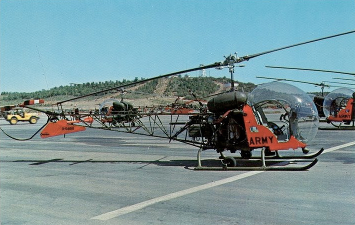 A group of red and black helicopters parked on top of a runway.